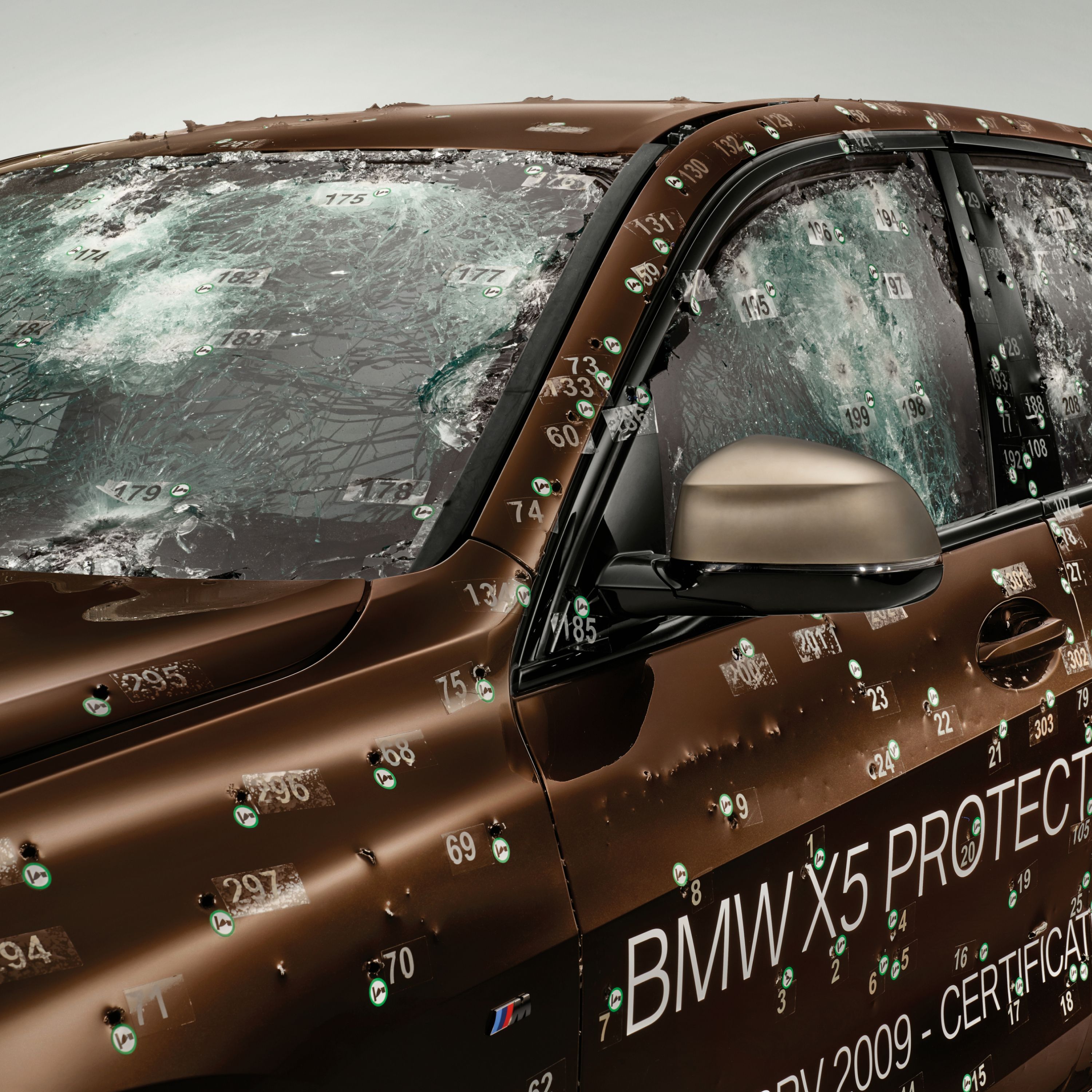 Close-up of the windscreen and side window with protective glass and bullet holes after a ballistic test 