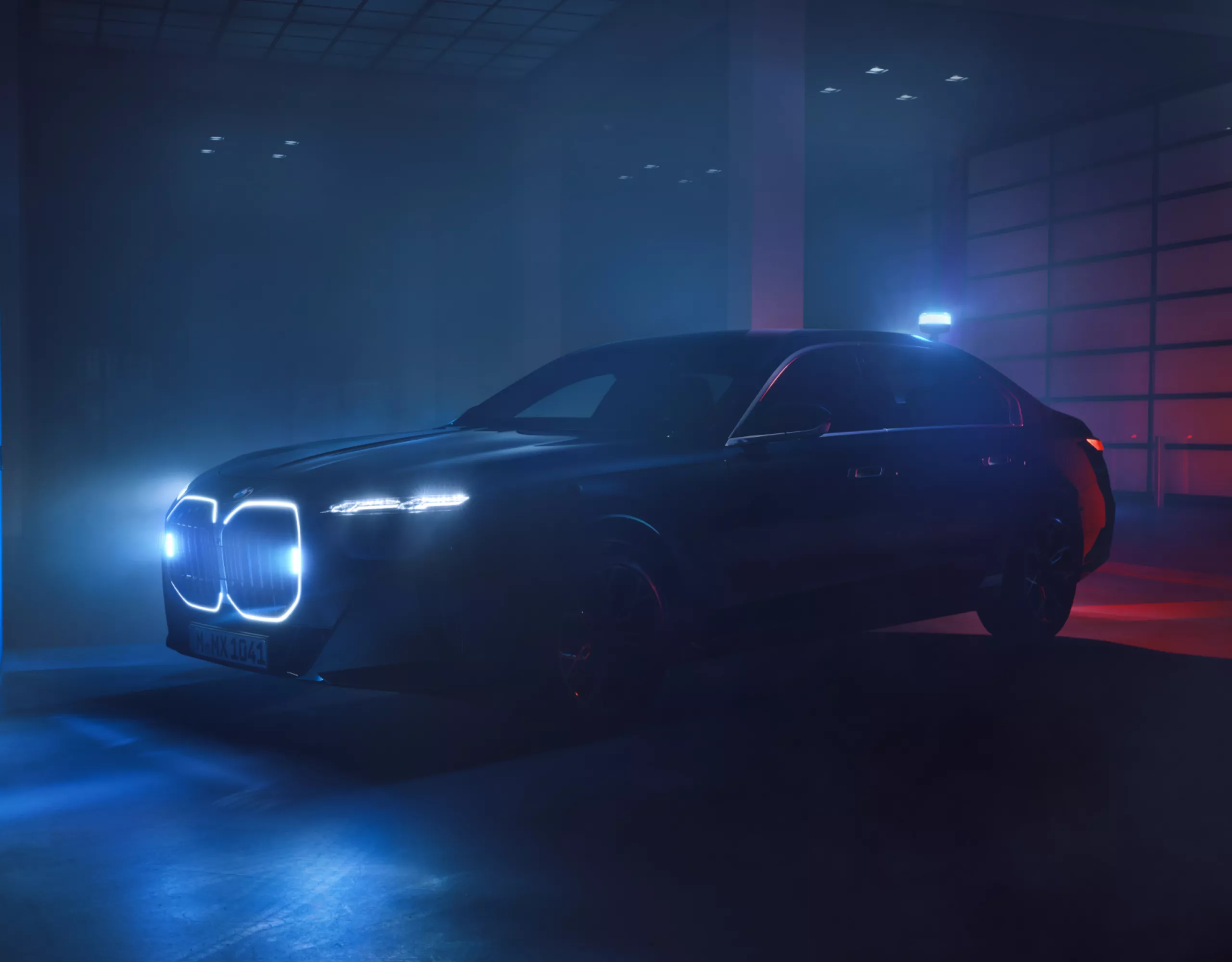 Un véhicule de protection spéciale BMW avec calandre illuminée est stationné dans un intérieur sombre