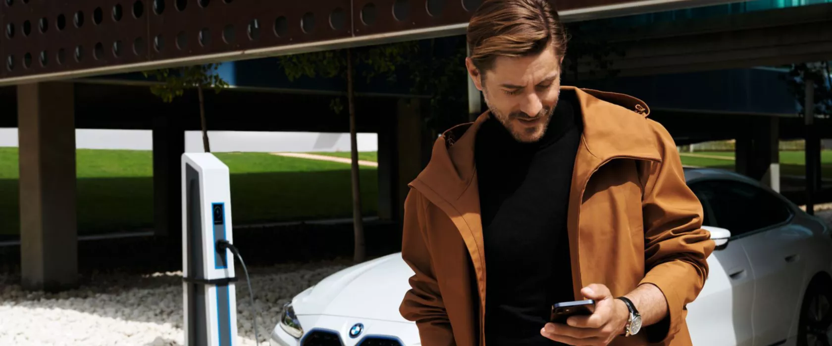 Man in front of BWW iX uses My BMW app on smartphone