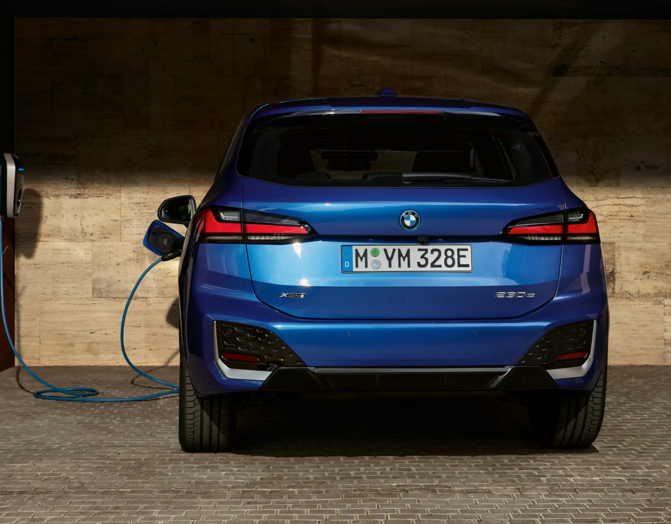 A BMW 2 Active Tourer wallboxra csatlakoztatva, egy nyitott garázsban