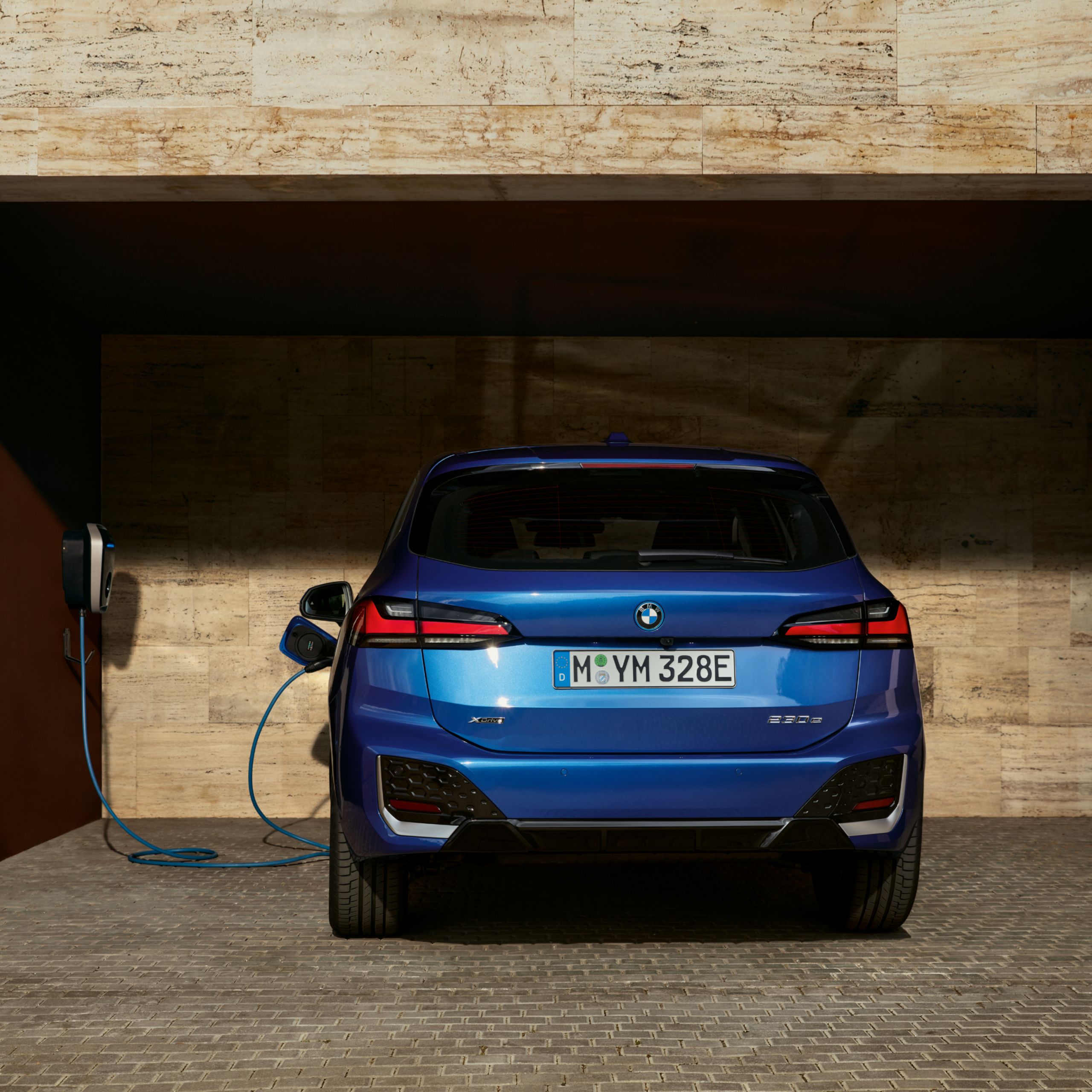 BMW 2 Reeks Active Tourer is bezig met opladen via een wallbox in een open garage