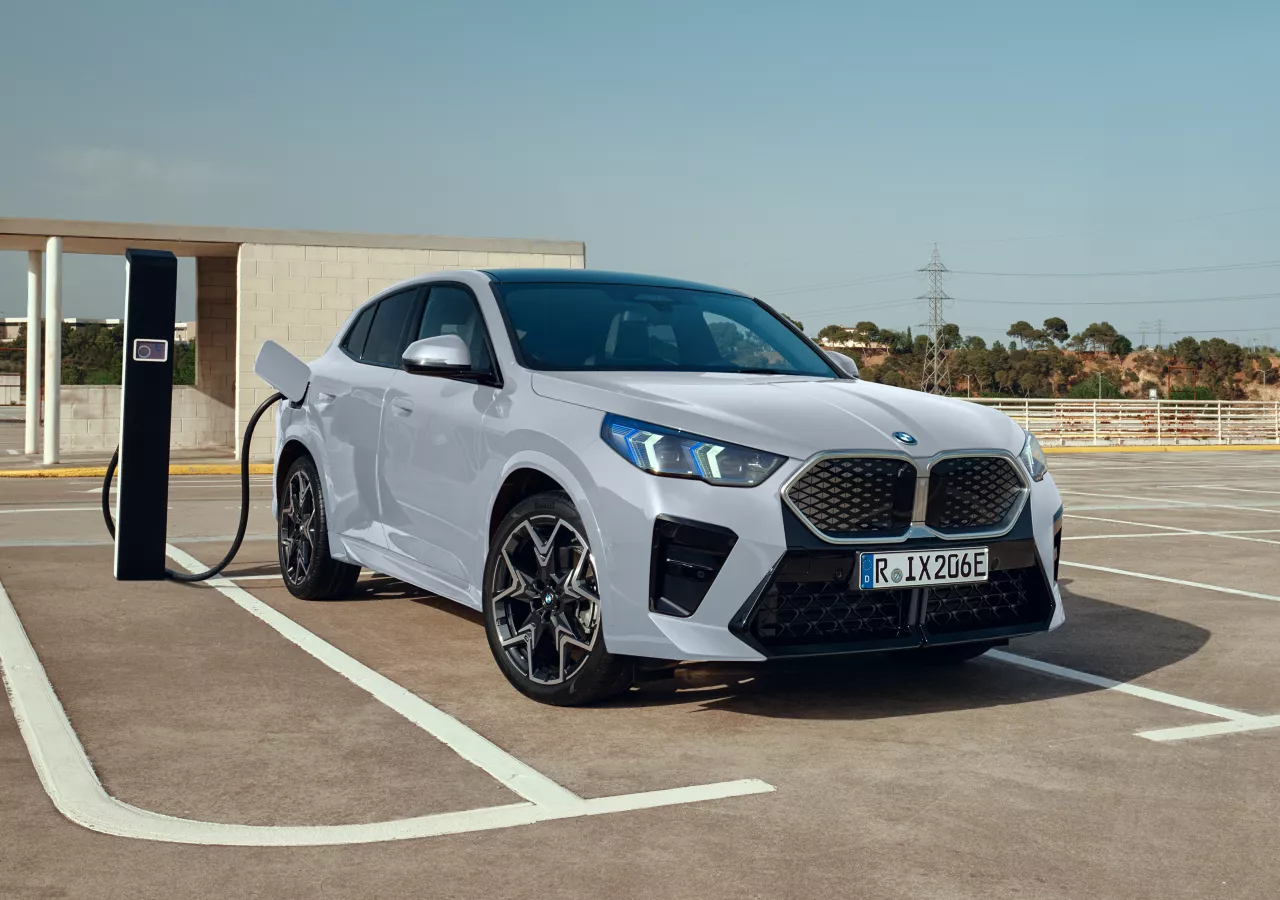  BMW iX2 100% elettrica in Brooklyn Grey presso una stazione di ricarica pubblica all'interno di un parcheggio