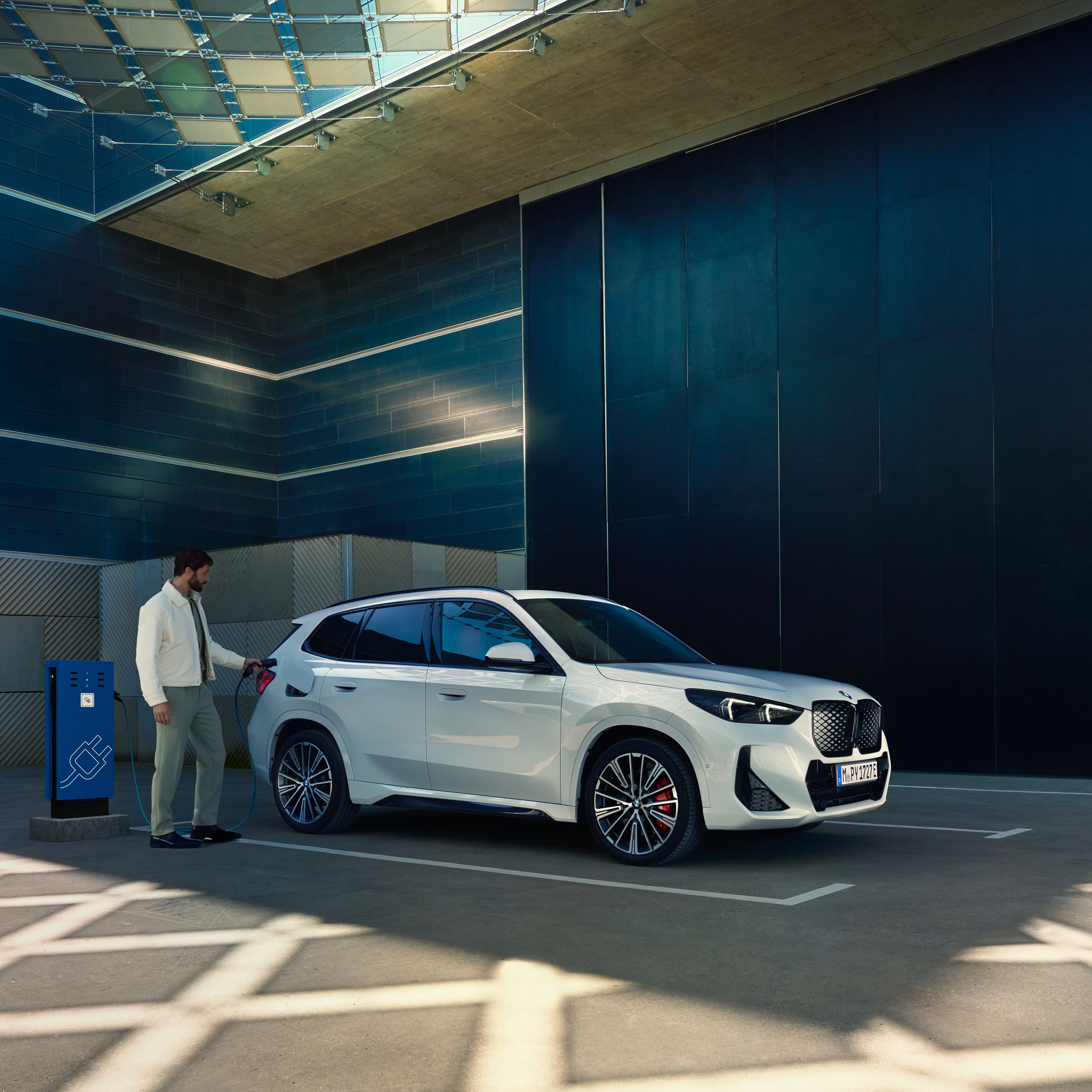 W pełni elektryczne BMW iX1 ładuje się na stacji ładowania.