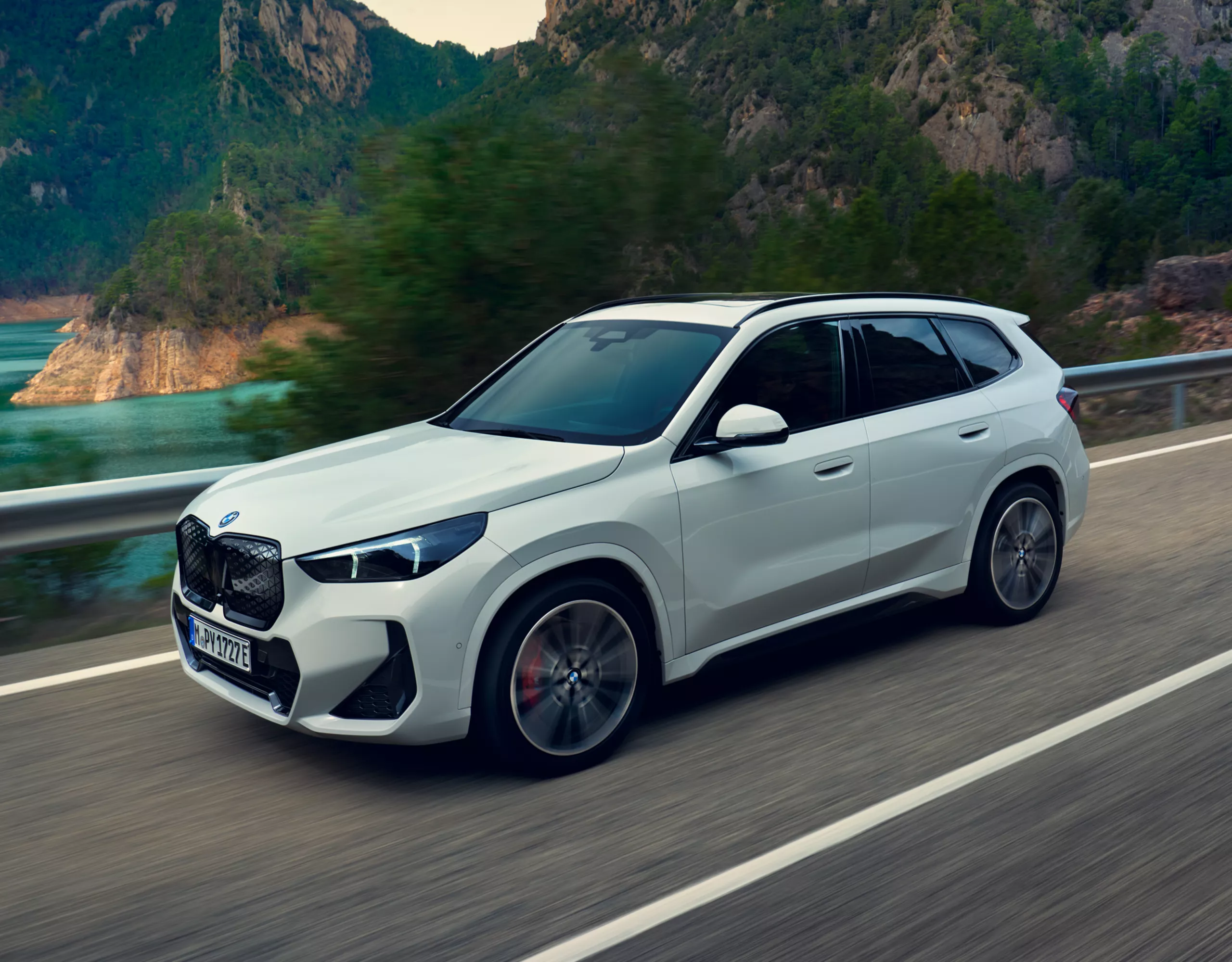 Ein weißer vollelektrischer BMW iX1 fährt auf einer Straße.