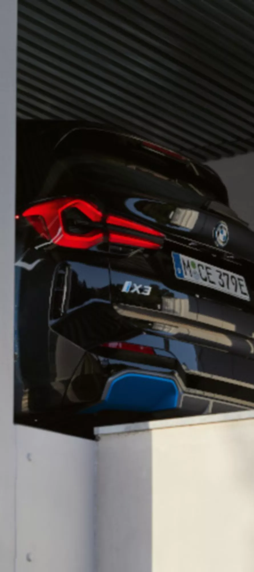 BMW iX3 preto visto pela traseira, estacionado numa área coberta junto a pilares brancos