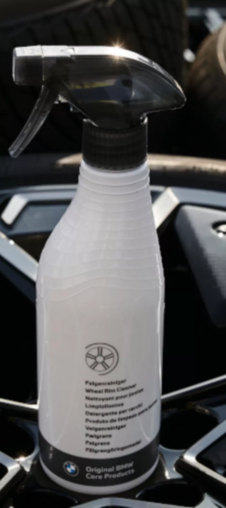 Frasco branco de produto de limpeza BMW sobre uma jante preta.