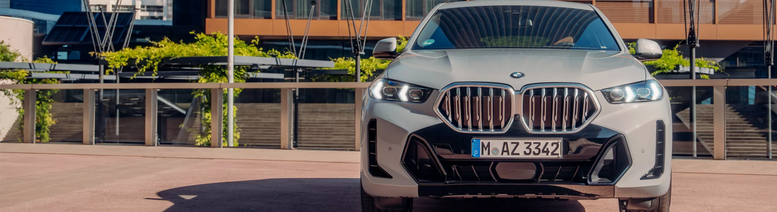 Um BMW X6 SUV está estacionado sob a luz do sol em frente a um prédio de tijolos