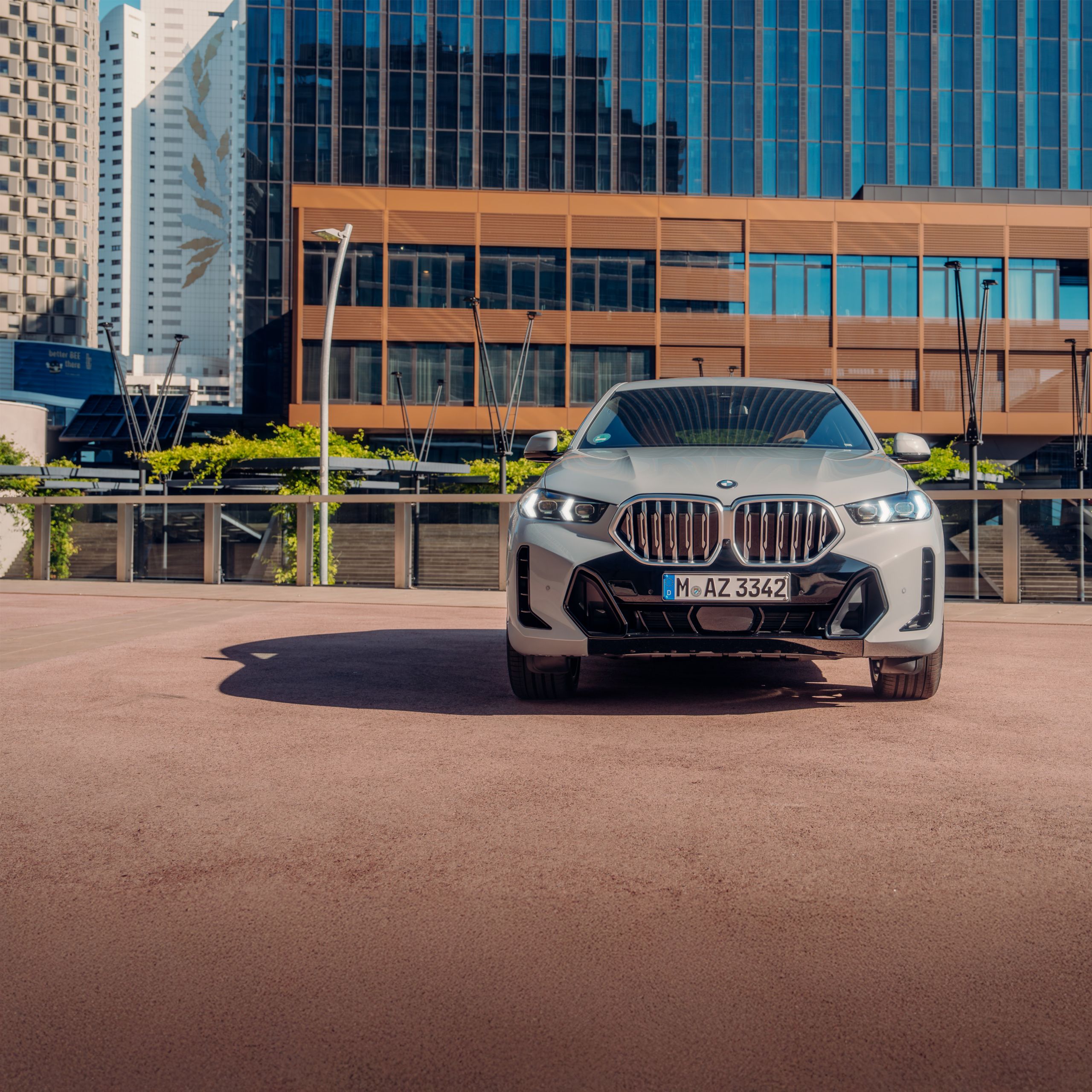 Um BMW X6 SUV está estacionado sob a luz do sol em frente a um prédio de tijolos
