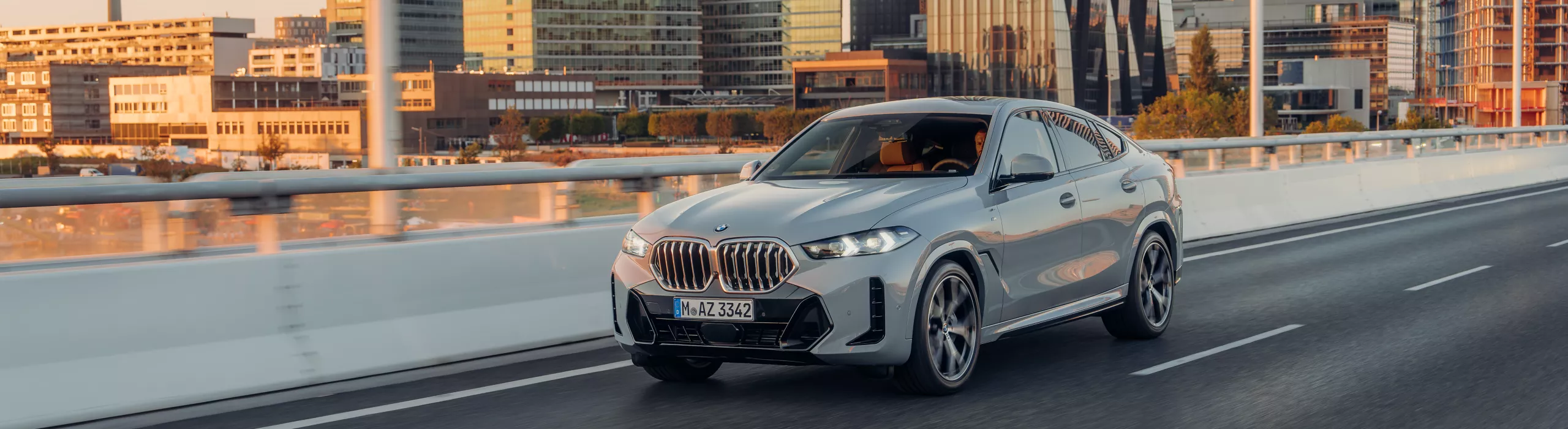 BMW X6 SUV กำลังขับขี่บนทางด่วนด้านหน้าวิวภูเขา
