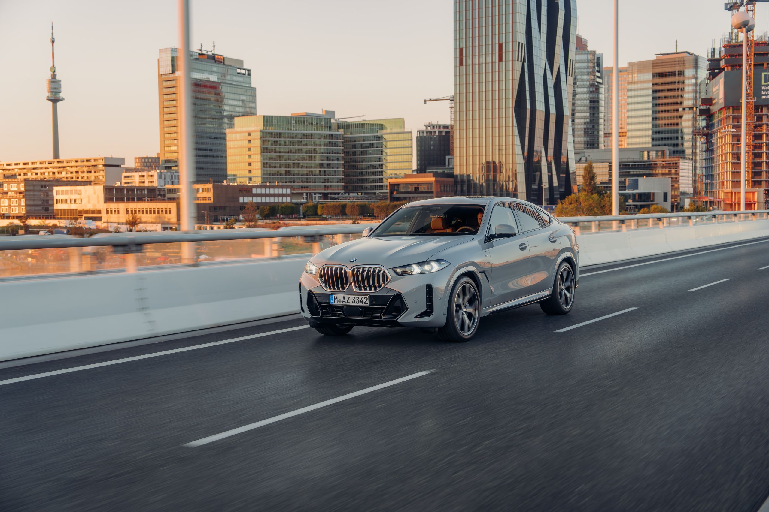BMW X6 SUV กำลังขับขี่บนทางด่วนด้านหน้าวิวภูเขา