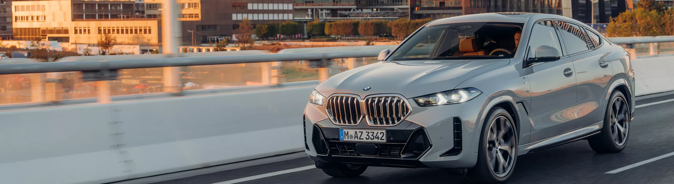 Um BMW X6 SUV está dirigindo em uma via expressa em frente a uma vista da montanha