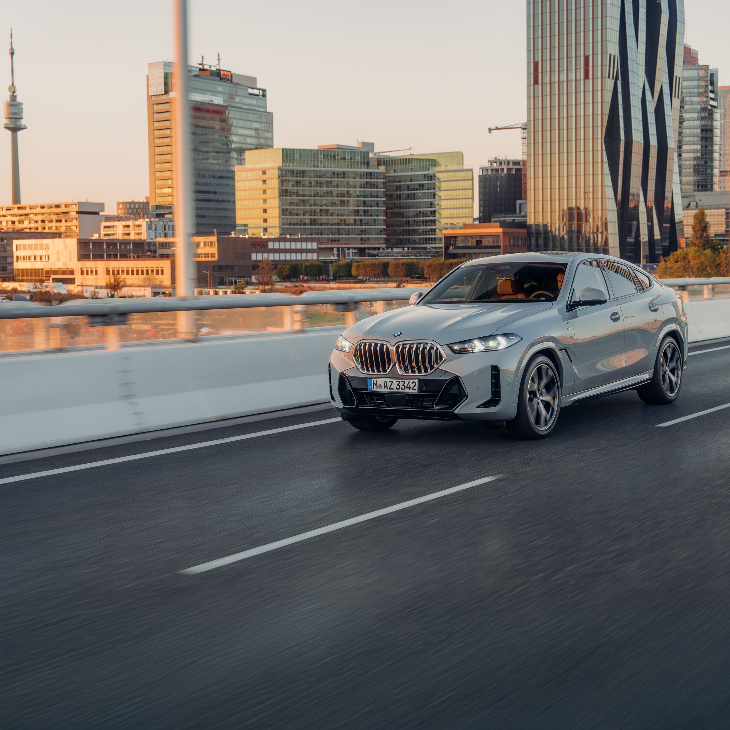 Um BMW X6 SUV está dirigindo em uma via expressa em frente a uma vista da montanha