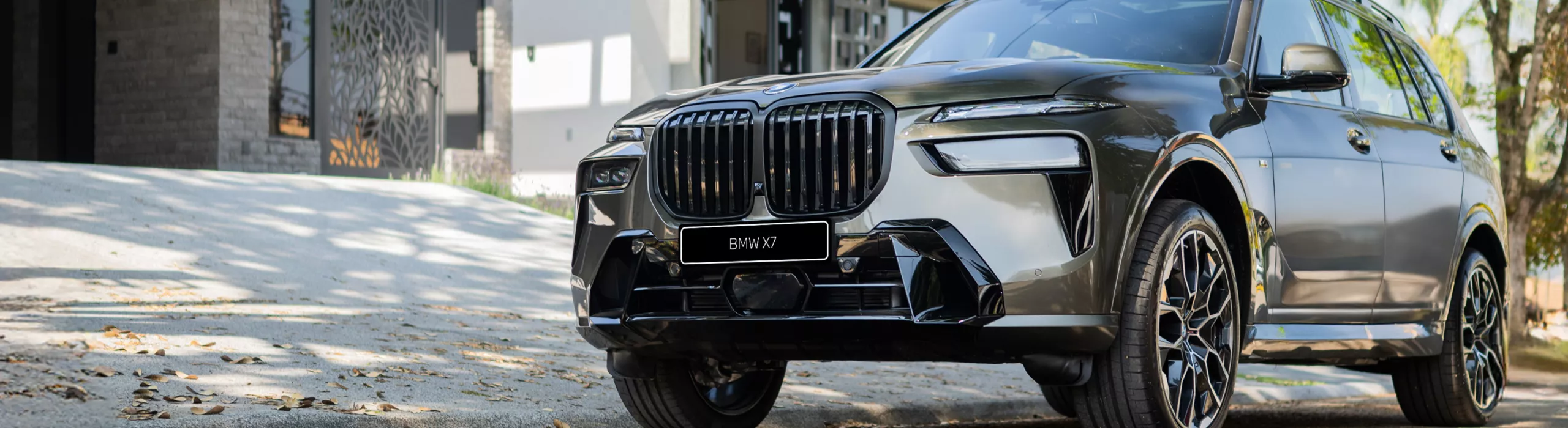 Um BMW X7 está estacionado em uma plataforma em frente a uma montanha rochosa.